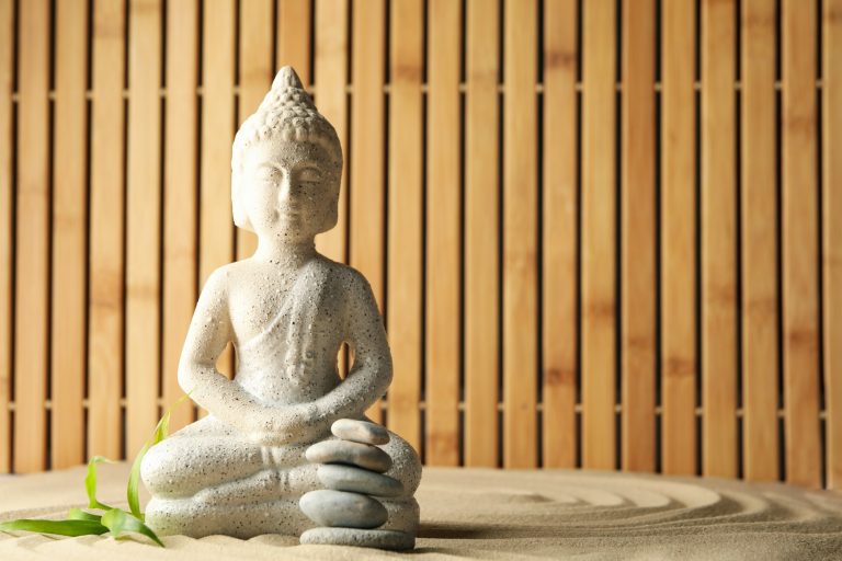 Buddha and leaf on sand background. Zen concept