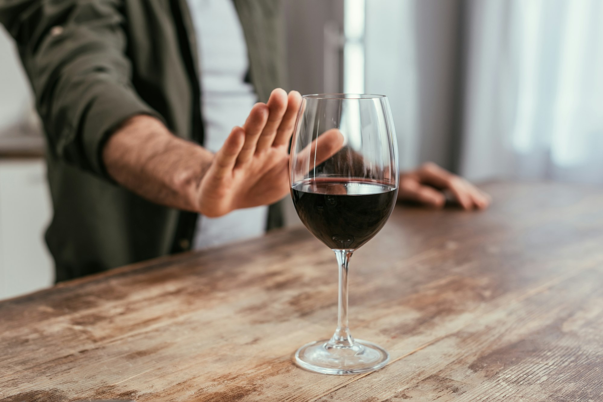 Cropped view of man pulling hand to wine glass on table