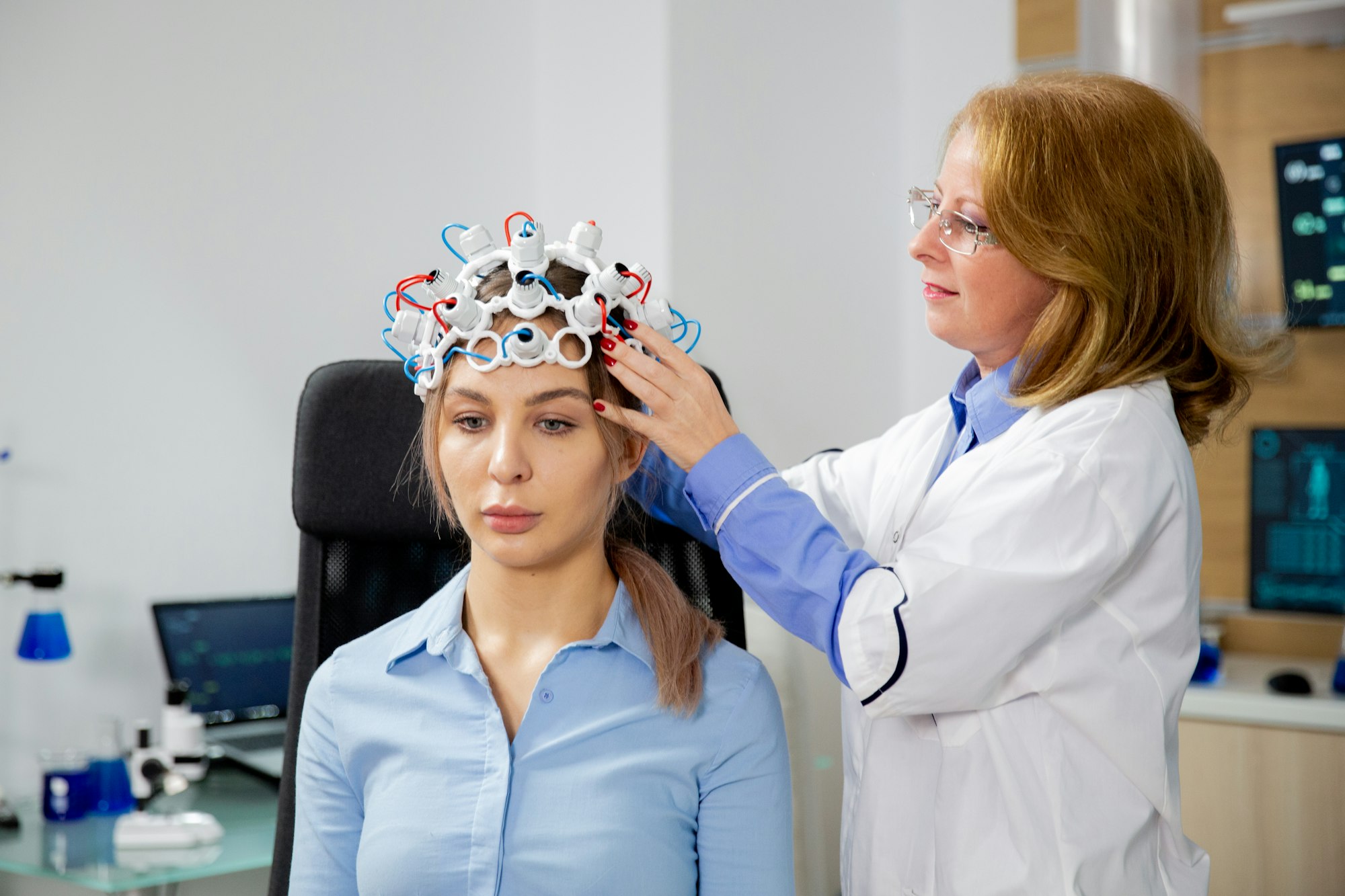 Female scientist who puts brain waves scanning helmet on a female patient