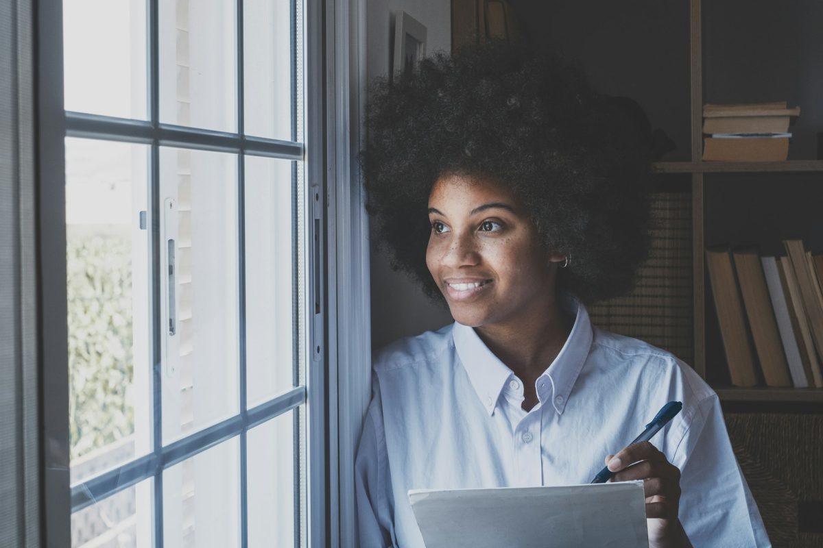 Smiling african american businesswoman in thoughts holding document and pen