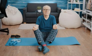 Aged man doing meditation while sitting in lotus position