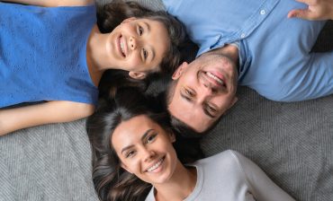 Happy family concept. Top view of happy family of three bonding to each other and smiling