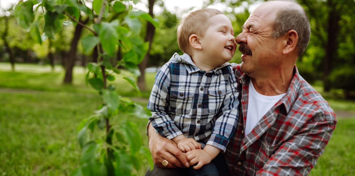 Planting family tree. Little boy helping his grandfather to plant tree while working together.