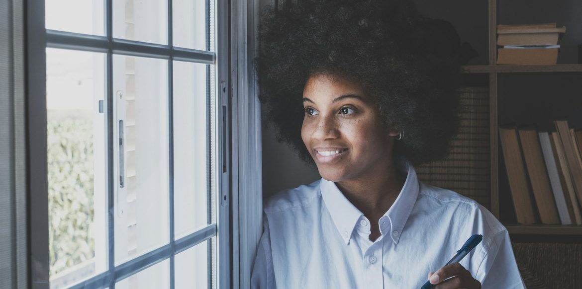 Smiling african american businesswoman in thoughts holding document and pen